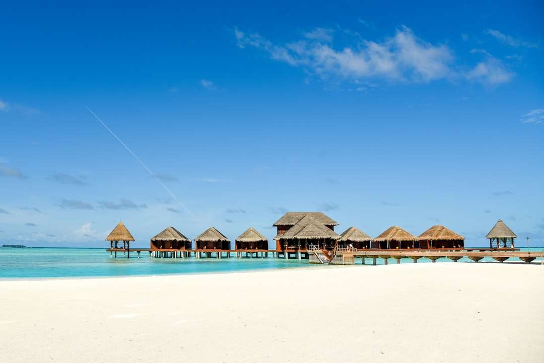 коричневые деревянные пляжные зонтики на пляже в дневное время пазл онлайн