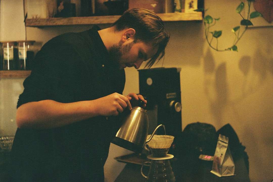 чоловік у чорній сорочці тримає чорно-сріблястий кавоварку онлайн пазл