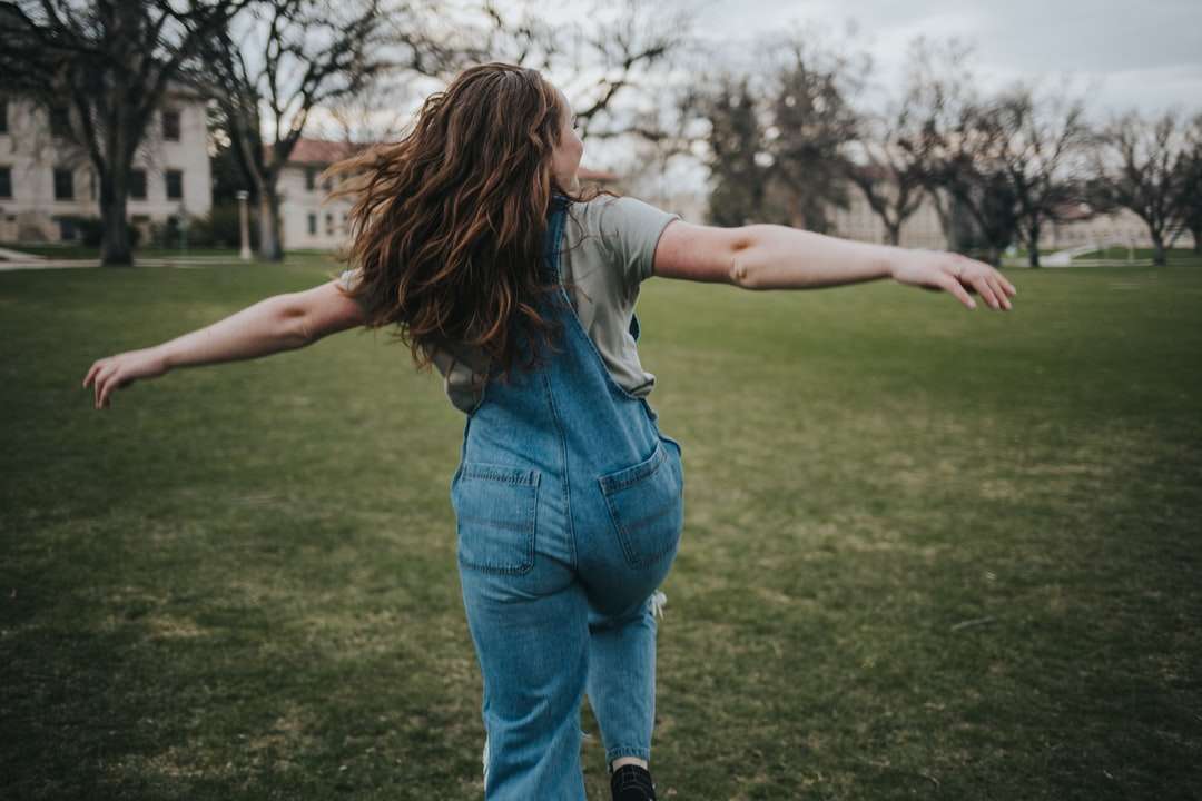 Жена в синя деним дънки, стоящи на зелено трева онлайн пъзел