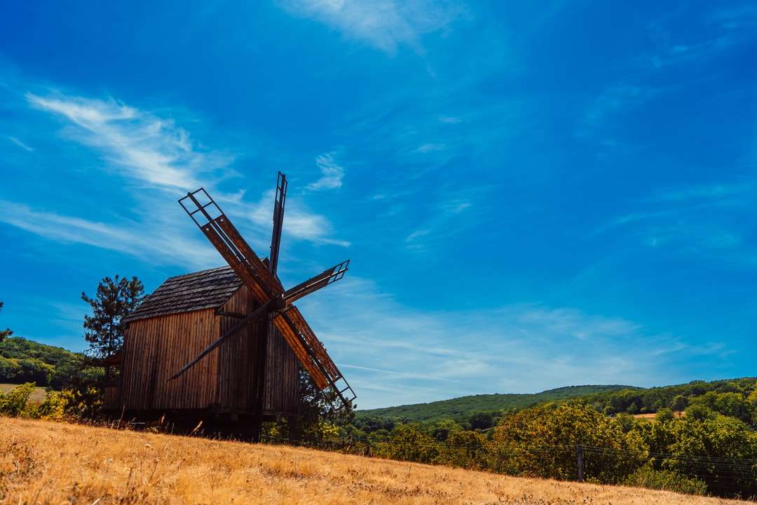 Hnědá dřevěná stodola na zelené trávě pole pod modrou oblohou online puzzle