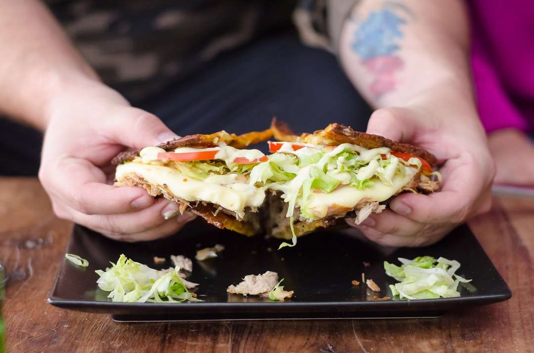 Persoana care deține burger cu salată și roșii jigsaw puzzle online