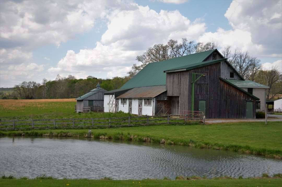 Hnědý dřevěný dům vedle řeky pod bílými mraky online puzzle