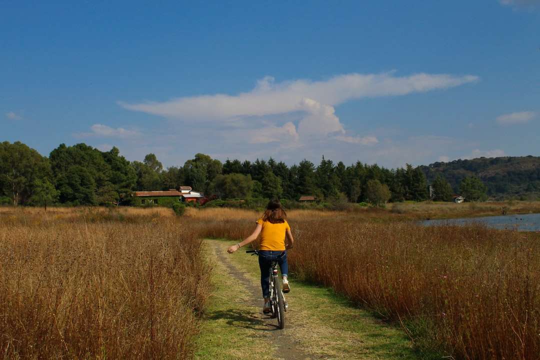 Mann im gelben Hemd Reiten Fahrrad auf grünem Grasfeld Puzzlespiel online