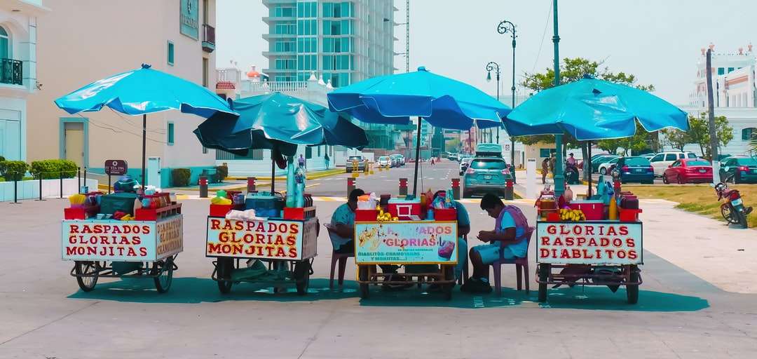 personnes assises sur des chaises rouges sous un parapluie bleu puzzle en ligne