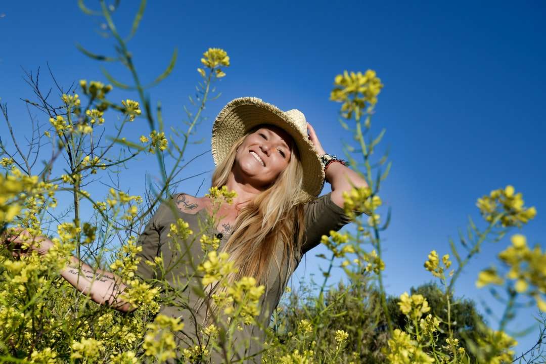 Flicka i brun solhatt som står på gult blomfält pussel på nätet