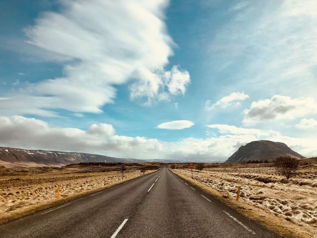 Estrada de asfalto cinza sob céu azul e nuvens brancas quebra-cabeças online