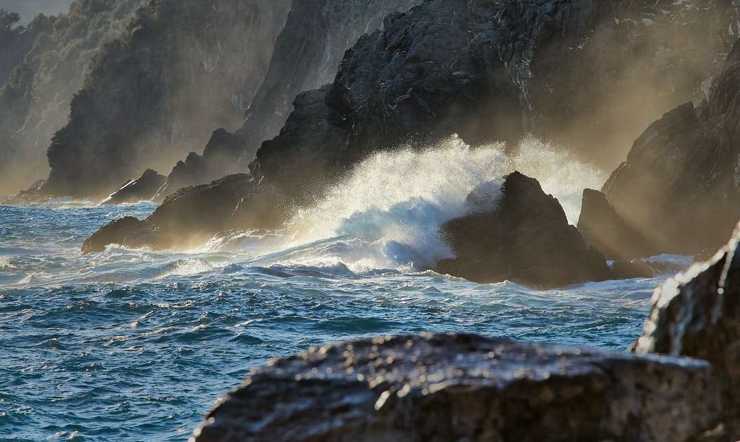 Valurile oceanului se prăbușesc pe țărm stâncos în timpul zilei puzzle online