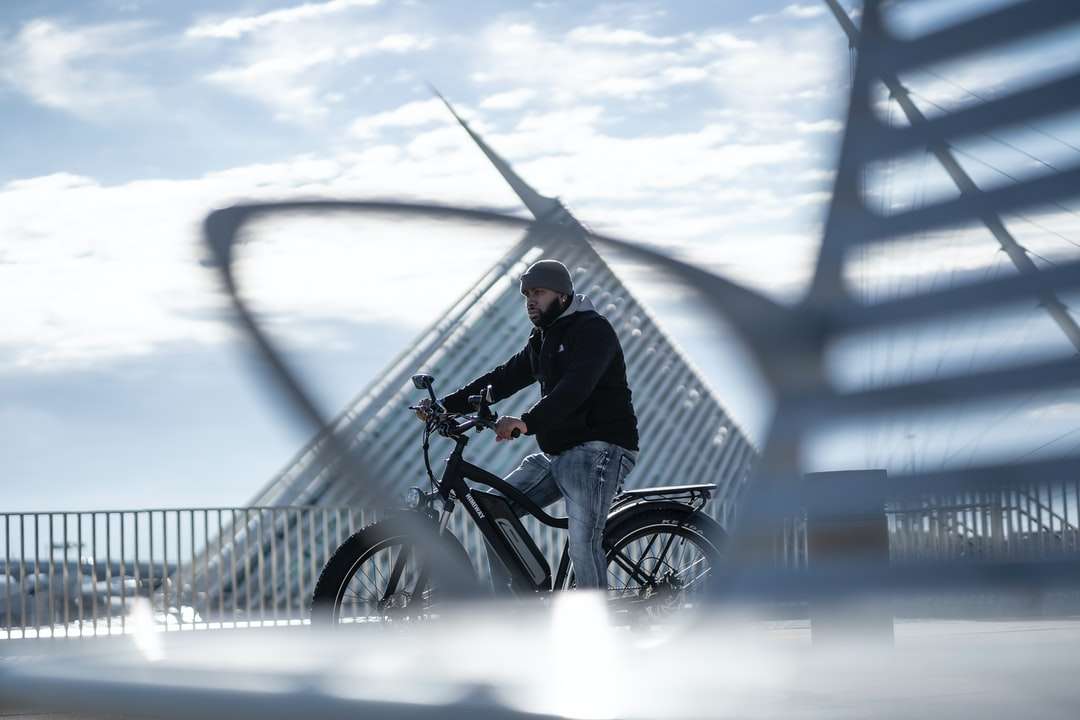 мъж в черно яке, каращ колело по покрита със сняг земя онлайн пъзел
