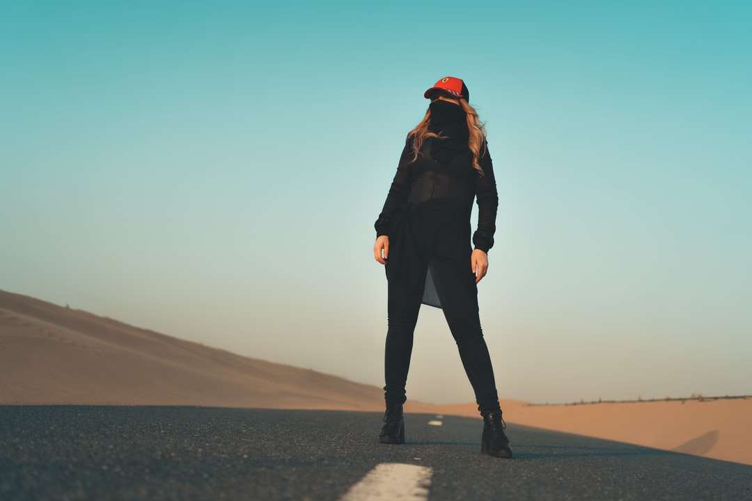 Frau in der schwarzen Jacke und der Hosen, die auf grauem Sand stehen Puzzlespiel online