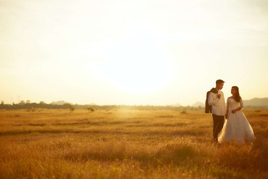 man en vrouw lopen overdag op bruin grasveld legpuzzel online