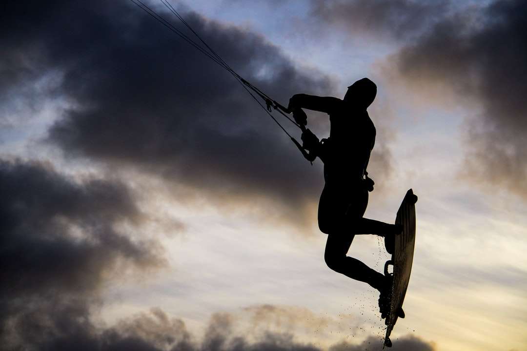 Σιλουέτα του ανθρώπου που οδηγεί στο skateboard κάτω από συννεφιασμένο ουρανό παζλ online