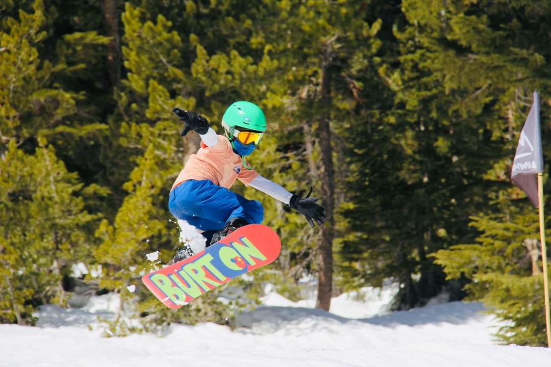 Az ember kék kabátban és piros sisak lovaglás piros snowboard kirakós online