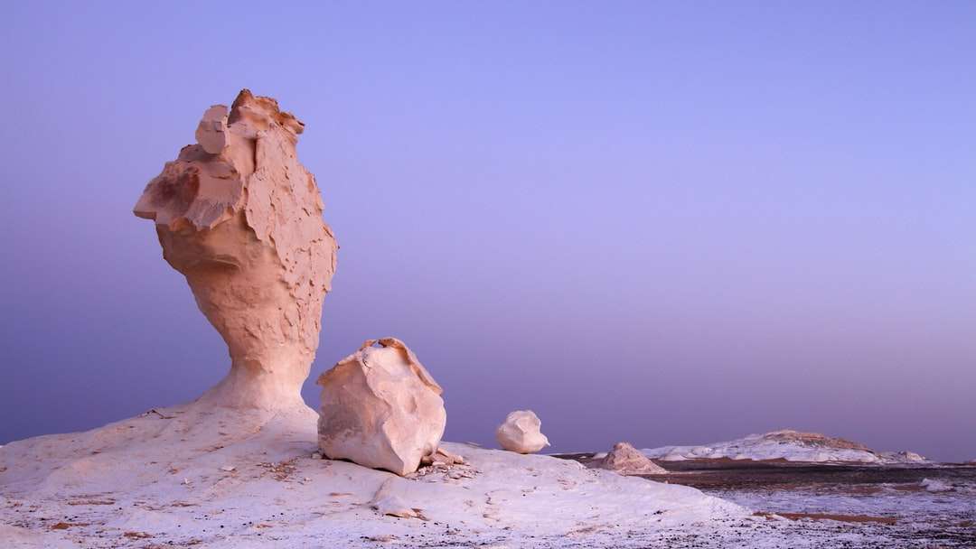 Formación de roca marrón en la arena blanca durante el día rompecabezas en línea
