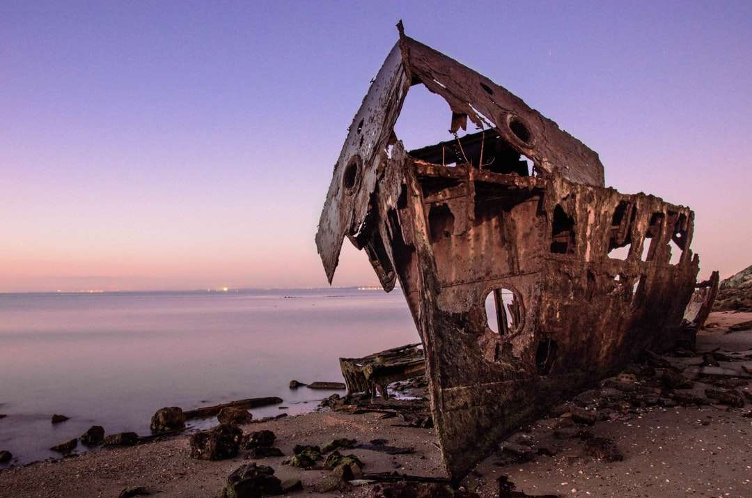 Hnědá dřevěná loď na břehu moře během dne online puzzle