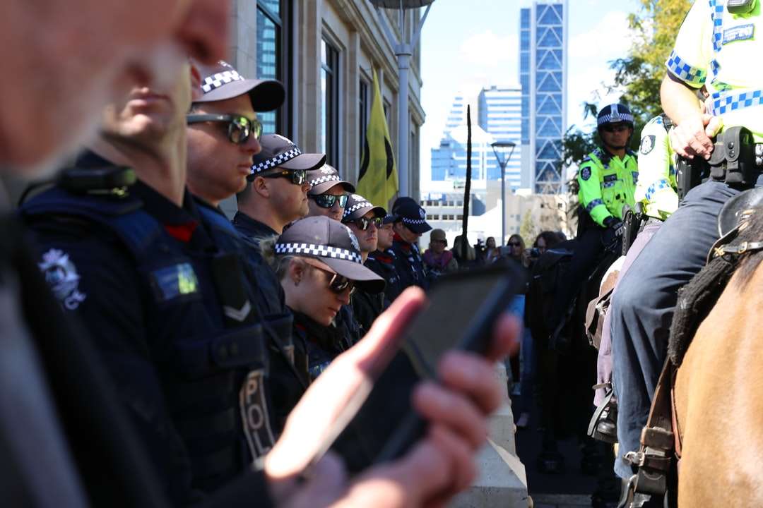 hombre con uniforme de policía negro sosteniendo un teléfono inteligente negro rompecabezas en línea