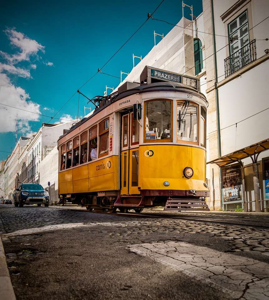 Gele en witte tram op weg dichtbij witte betonnen bouw legpuzzel online