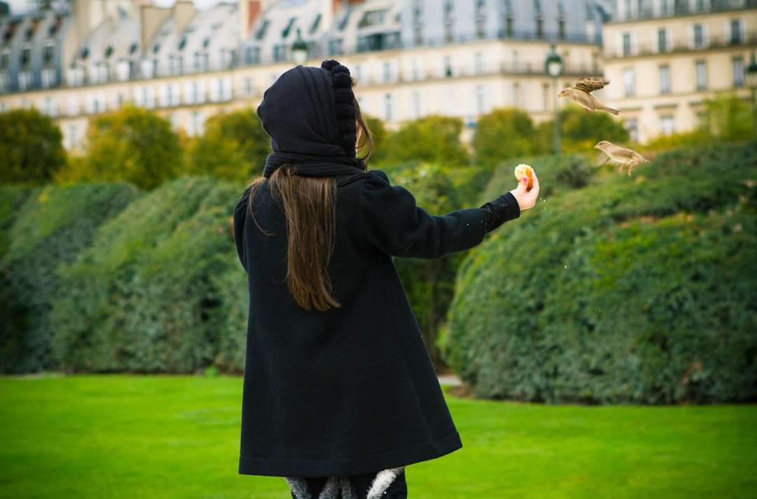 Γυναίκα σε μαύρο παλτό στέκεται σε πράσινο γρασίδι online παζλ