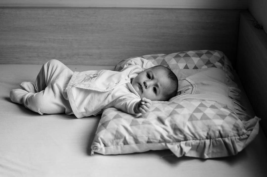 Grayscale foto van baby liggend op bed online puzzel