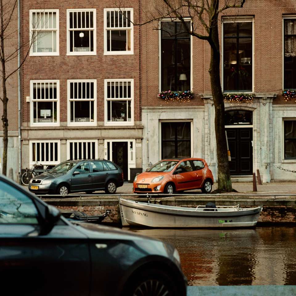 Автомобили, паркирани пред кафяво и бяла сграда онлайн пъзел