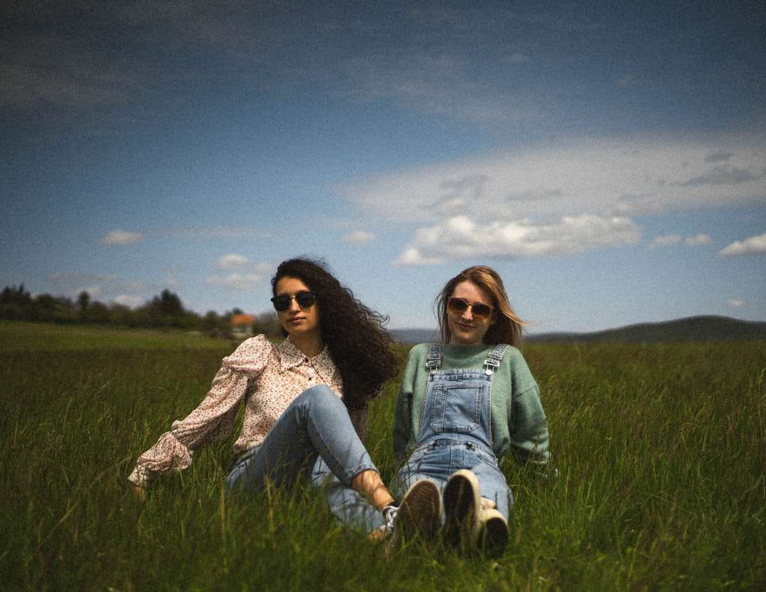 2 γυναίκες που κάθονται σε πράσινο χόρτο πεδίο κάτω από τον μπλε ουρανό online παζλ