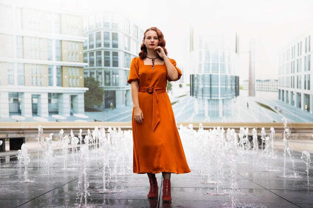 γυναίκα με πορτοκαλί φόρεμα που στέκεται στο σιντριβάνι online παζλ