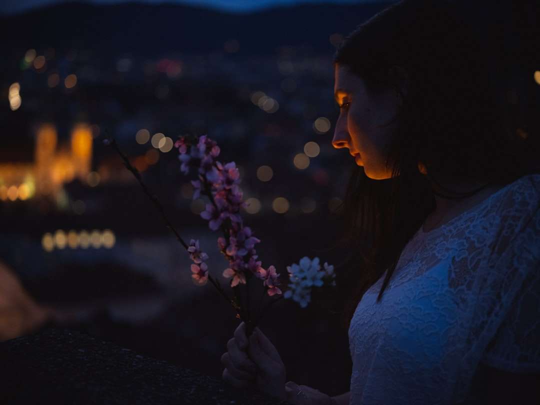 夜の間に紫色の花を保持している白いシャツの女性 ジグソーパズルオンライン