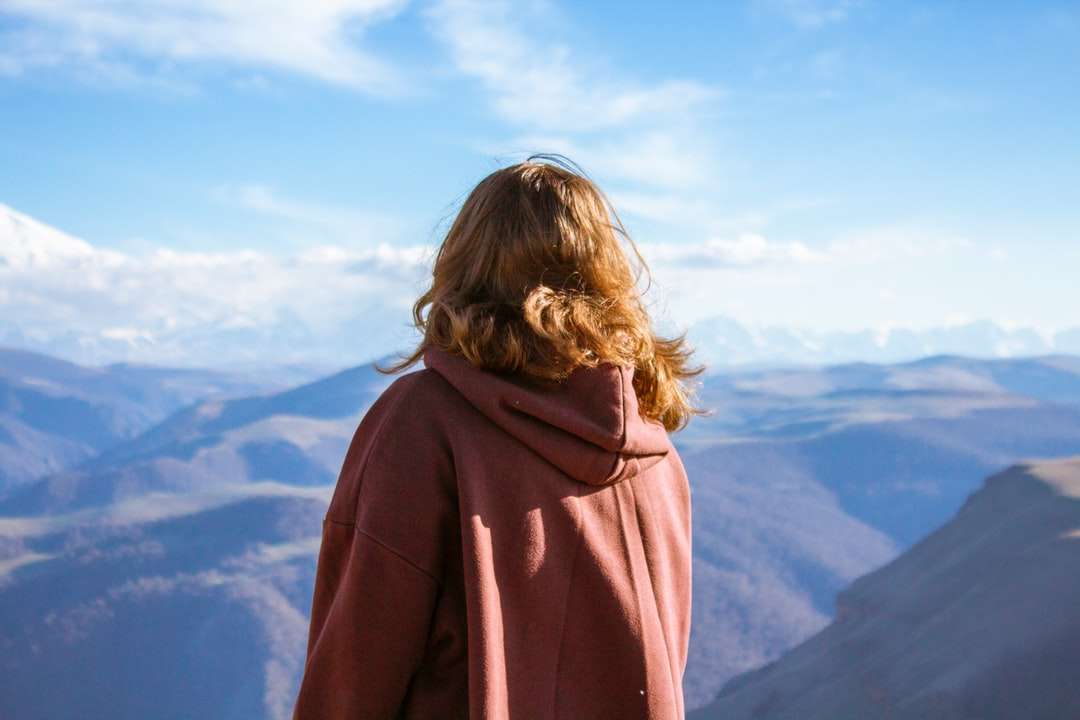 Γυναίκα σε καφέ hoodie στέκεται στην κορυφή του βουνού παζλ online