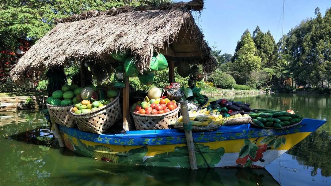 Capanna di Nipa marrone circondata da frutta sulla barca di legno verde puzzle online