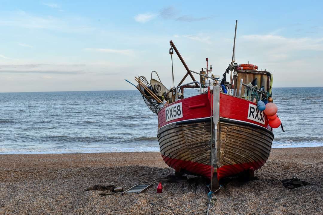 Καφέ και κόκκινο βάρκα στην παραλία κατά τη διάρκεια της ημέρας online παζλ