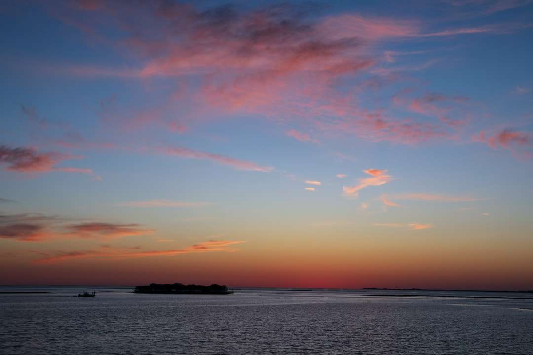 Cuerpo de agua bajo naranja y cielo azul durante la puesta del sol. rompecabezas en línea