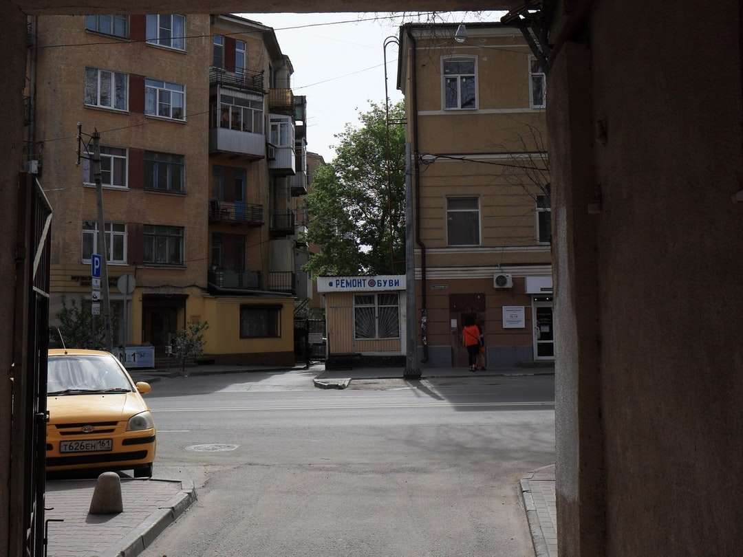 Желтая машина припаркована рядом с коричневым бетонным зданием онлайн-пазл