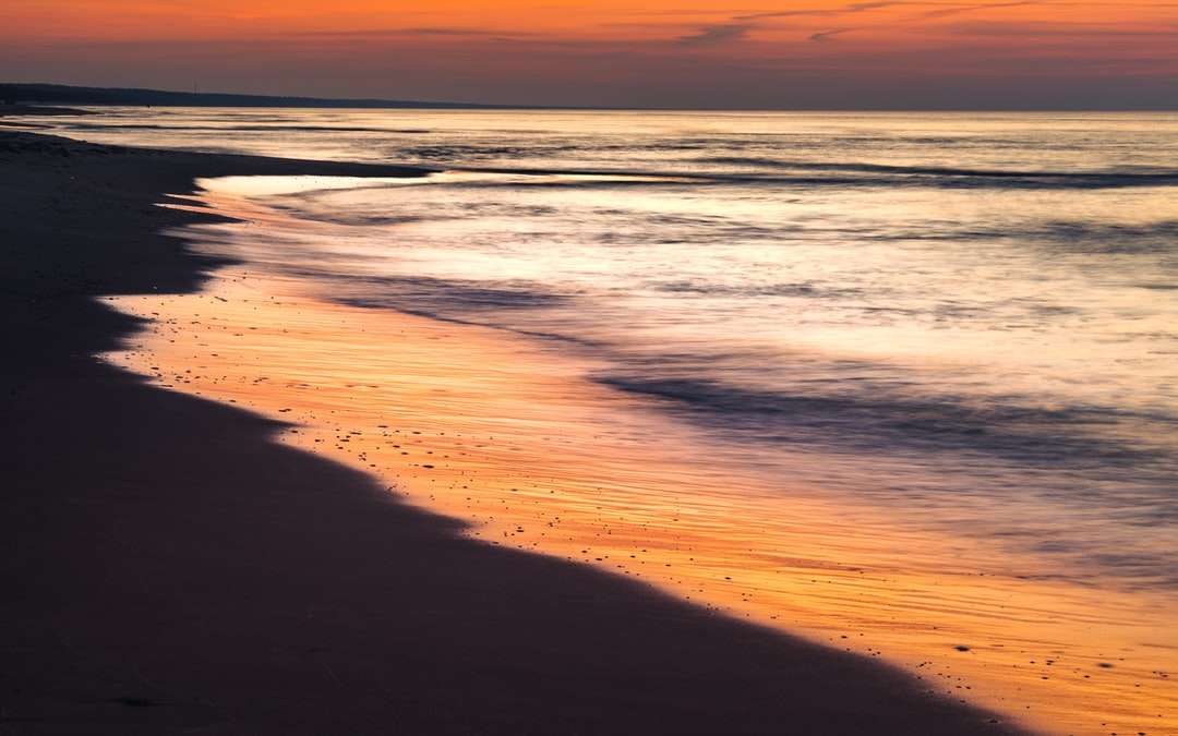 Ondas do oceano batendo na costa durante o pôr do sol puzzle online