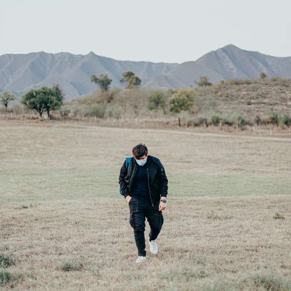 緑の芝生のフィールドを歩く黒いジャケットの男 ジグソーパズルオンライン