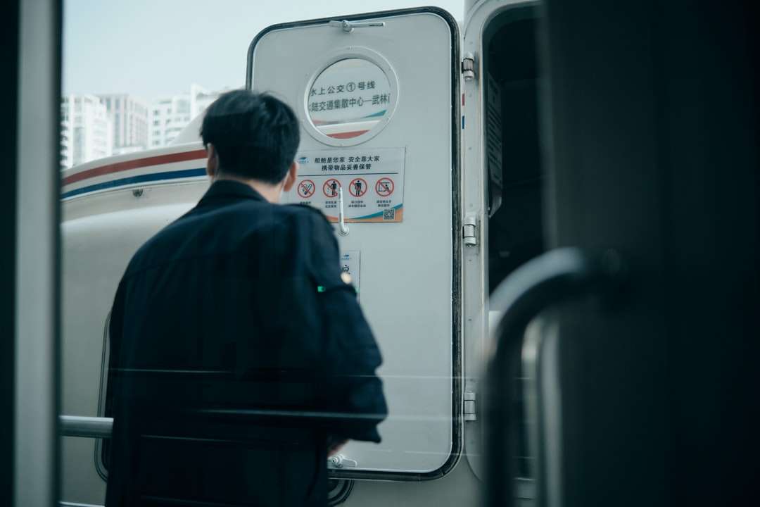 женщина в синей куртке стоит перед бело-синим автобусом онлайн-пазл