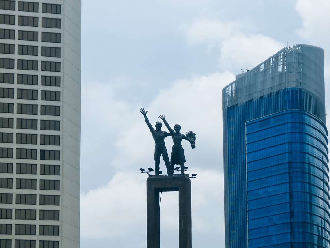 Μαύρο άγαλμα του ανθρώπου στην κορυφή του κτιρίου παζλ online