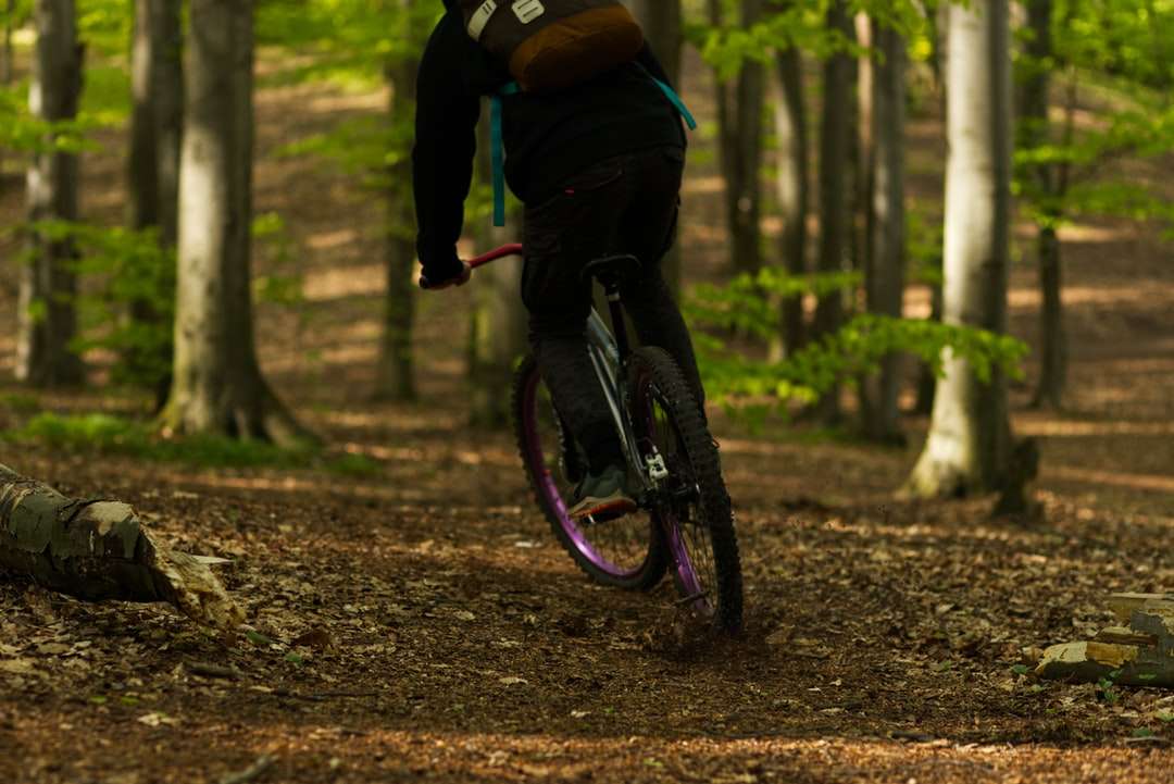 Човек в черното яке езда велосипед в гората през деня онлайн пъзел