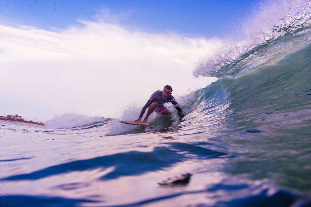 Hombre en pantalones cortos blancos que practica surf en las olas del mar durante el día rompecabezas en línea