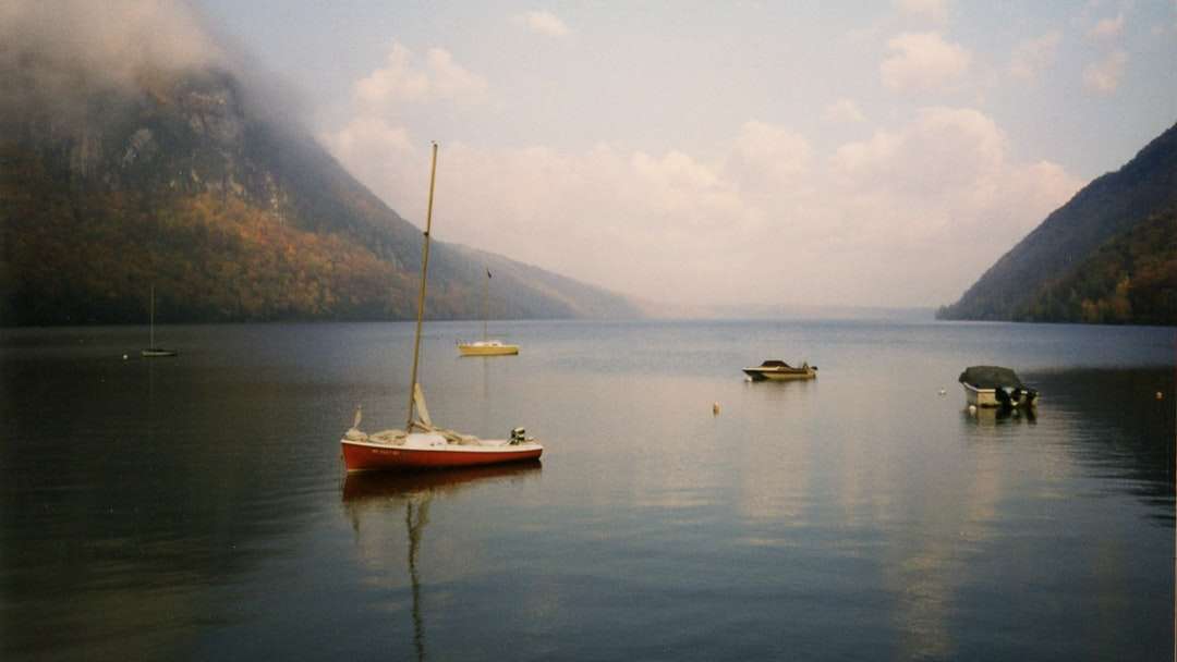 Barca albă și brună pe apă lângă munte în timpul zilei puzzle online