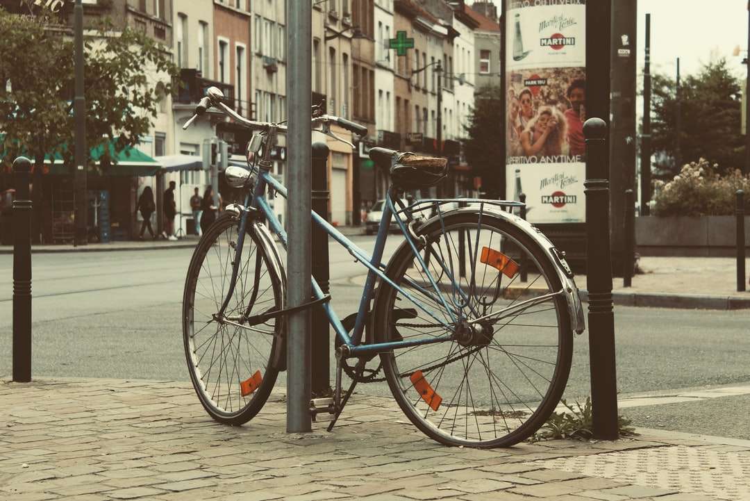 Vélo de ville bleue garée à côté de la clôture en métal noir puzzle en ligne