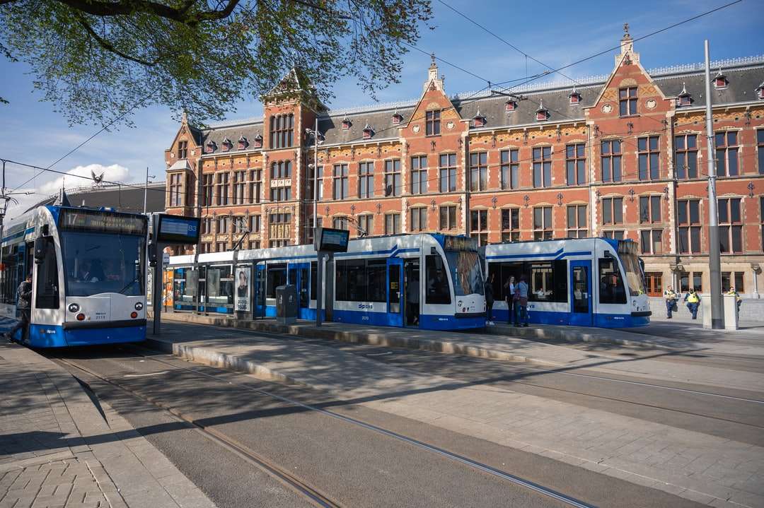 Blauwe en gele tram op weg dichtbij bruin gebouw online puzzel