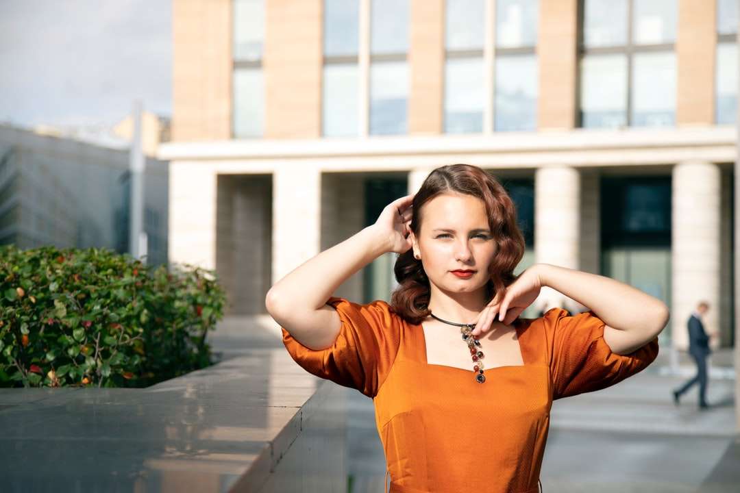 Vrouw in Oranje Shirt met lange mouwen die zich op stoep bevindt online puzzel