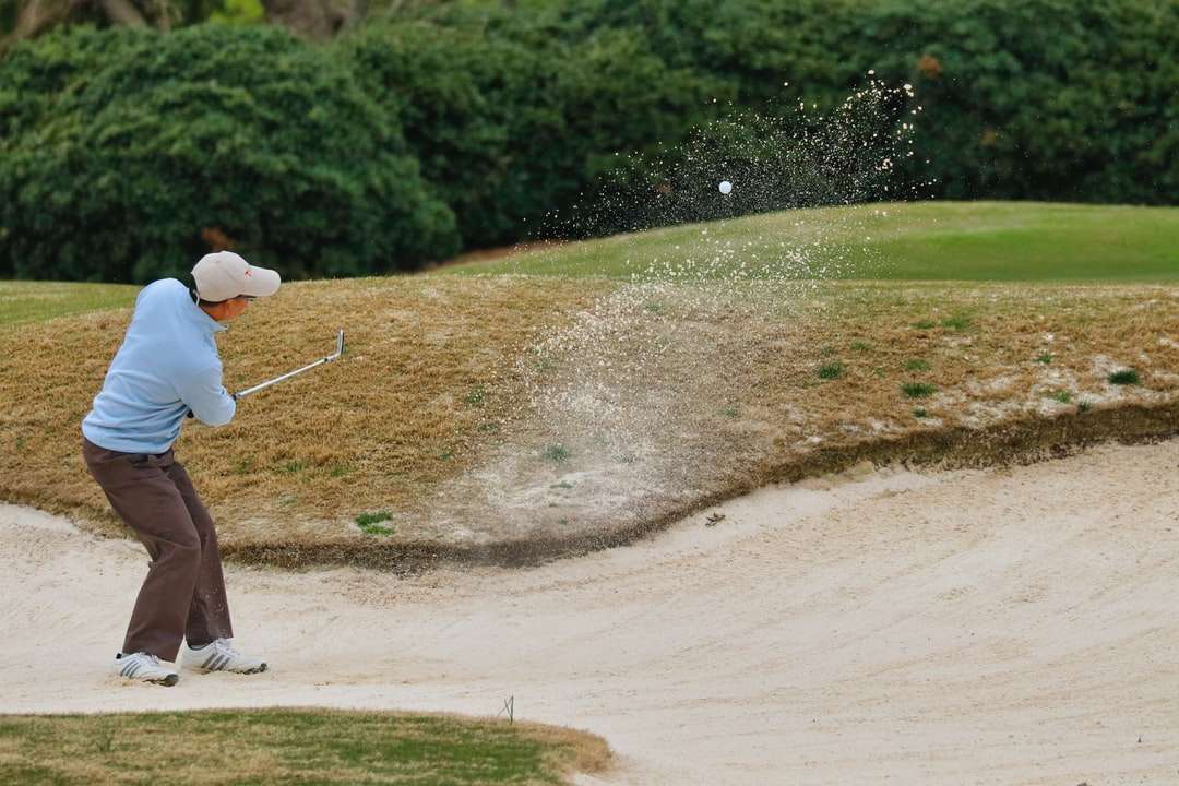 Persona en camisa blanca y pantalones marrones con club de golf rompecabezas en línea