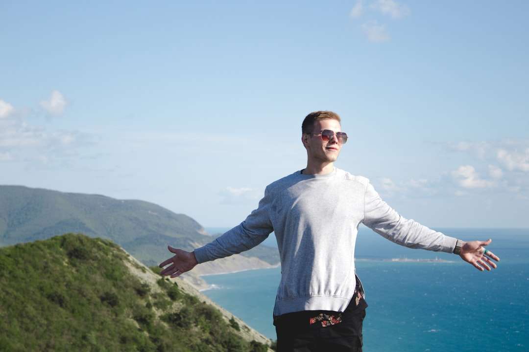 uomo in camicia bianca a maniche lunghe in piedi sulla montagna verde puzzle online