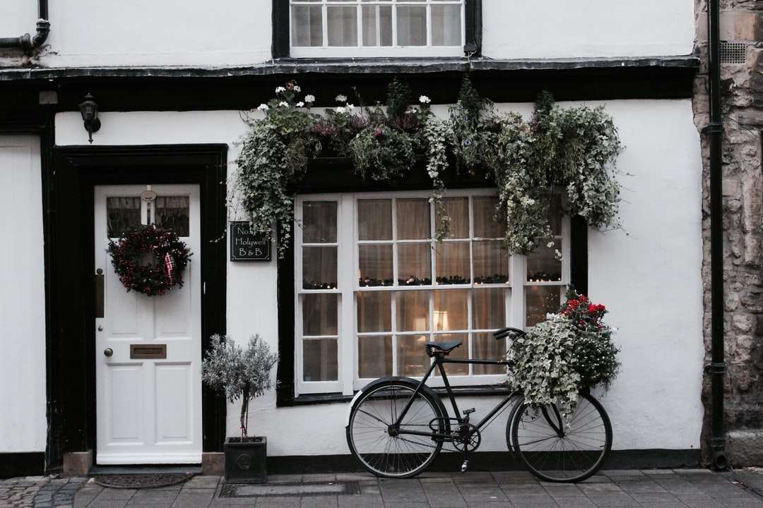 Μαύρο ποδήλατο πόλης σταθμευμένο δίπλα σε λευκό και καφέ σπίτι παζλ online