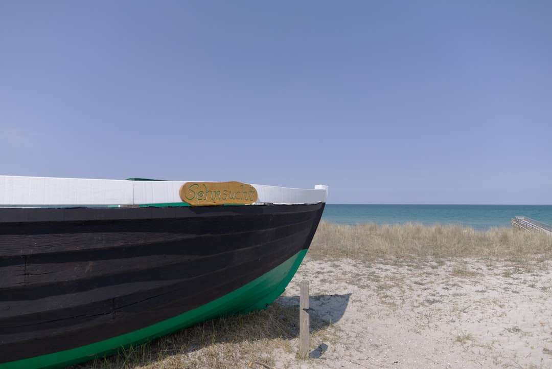 Barco azul y blanco en la orilla de la playa durante el día rompecabezas en línea