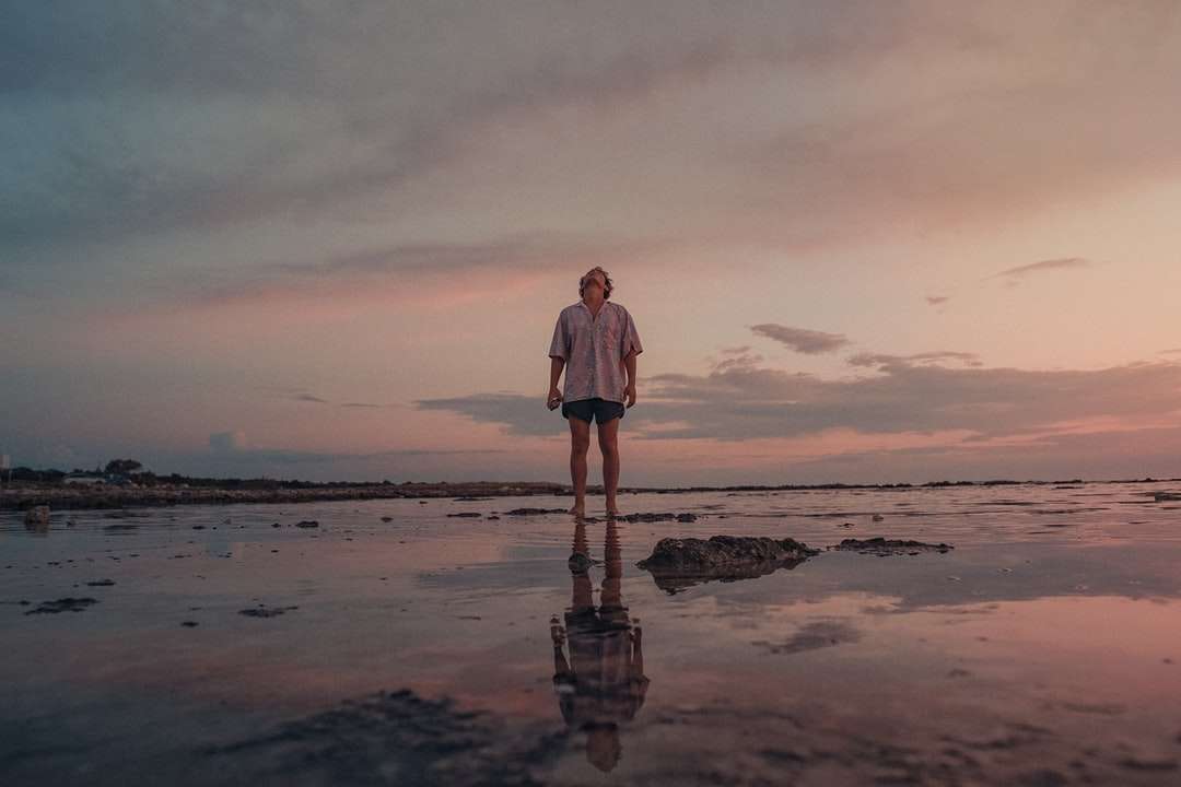 donna in abito bianco in piedi sulla spiaggia durante il tramonto puzzle online