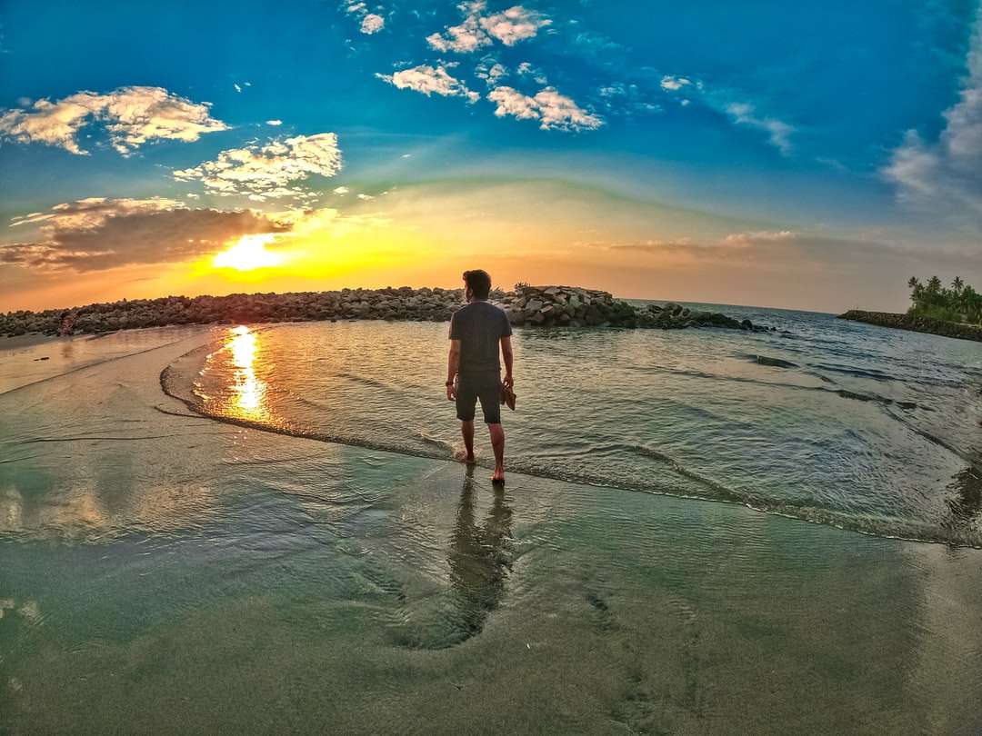 Man en vrouw die op strand lopen tijdens zonsondergang online puzzel