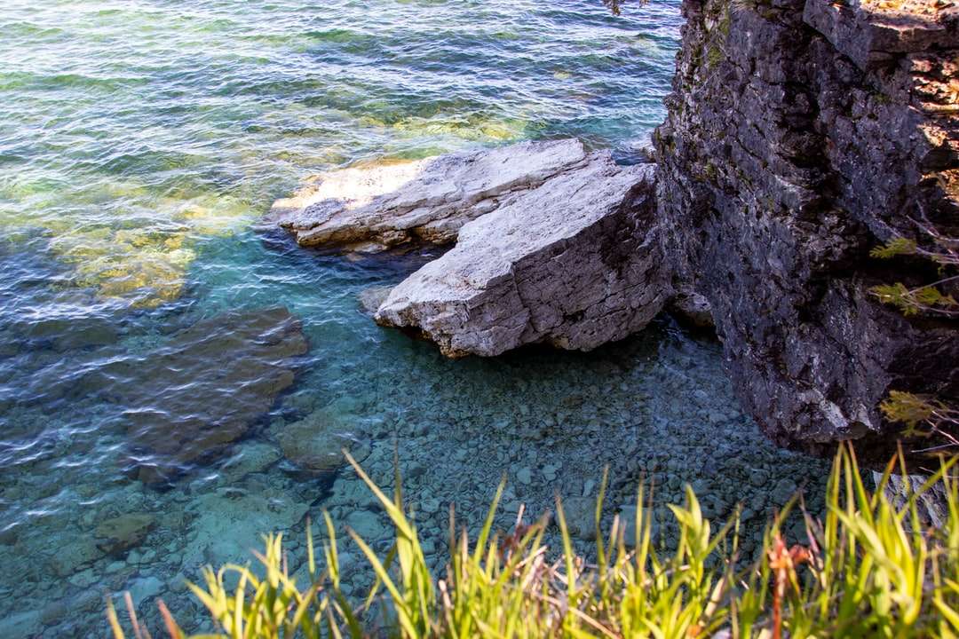 Formação de rocha cinza ao lado do corpo da água durante o dia quebra-cabeças online