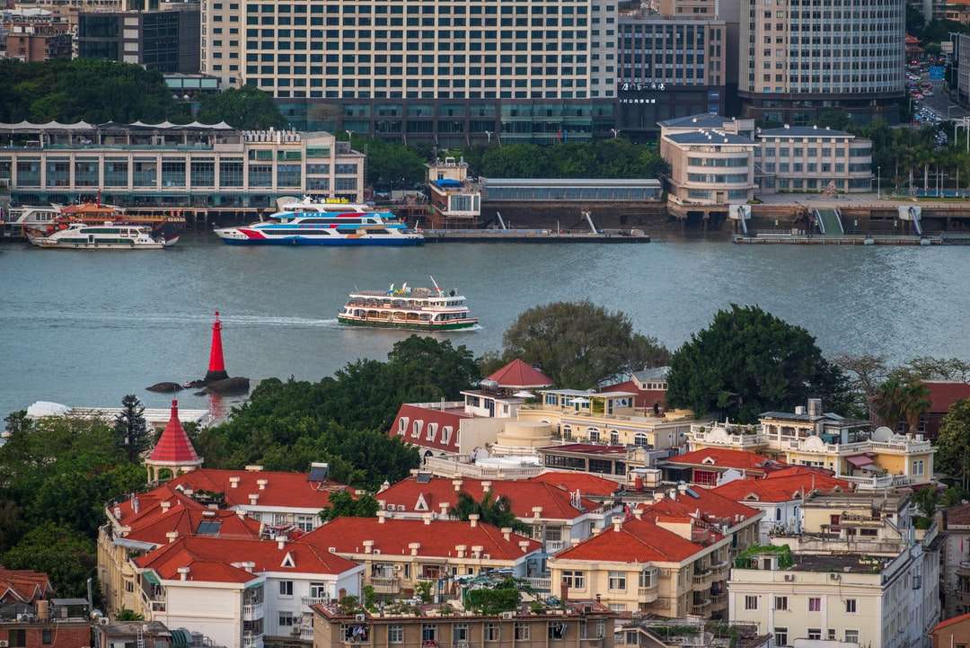 Vit och blå båt på vatten nära stadsbyggnader Pussel online