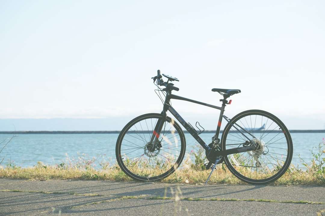 чорно-сірий дорожній велосипед на сірій бетонній дорозі біля тіла онлайн пазл